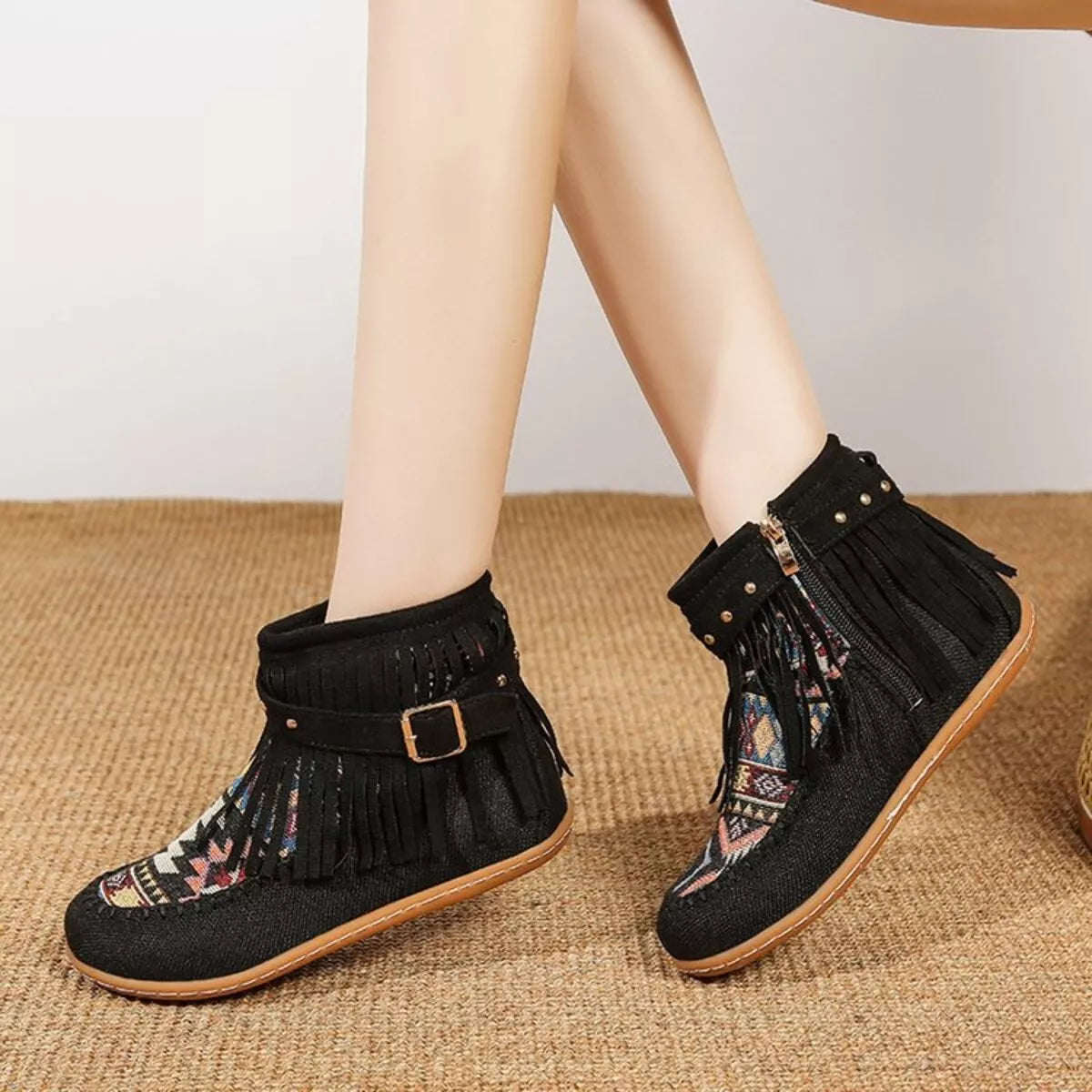 Black fringe ankle boots with side zipper, buckle strap, and patterned side panel design