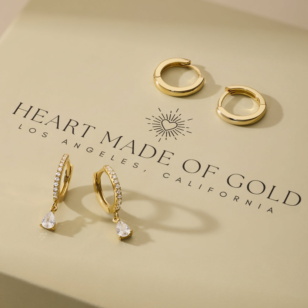 Gold-tone hoop earrings with pear-shaped drop charms and clear stones, set