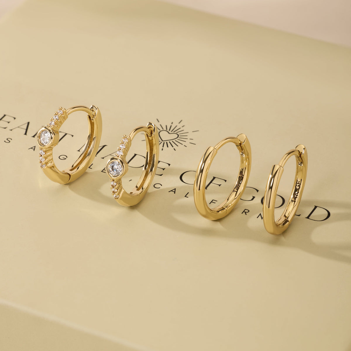 Gold bezel hoop earrings set with small round stones, shown as matching pairs