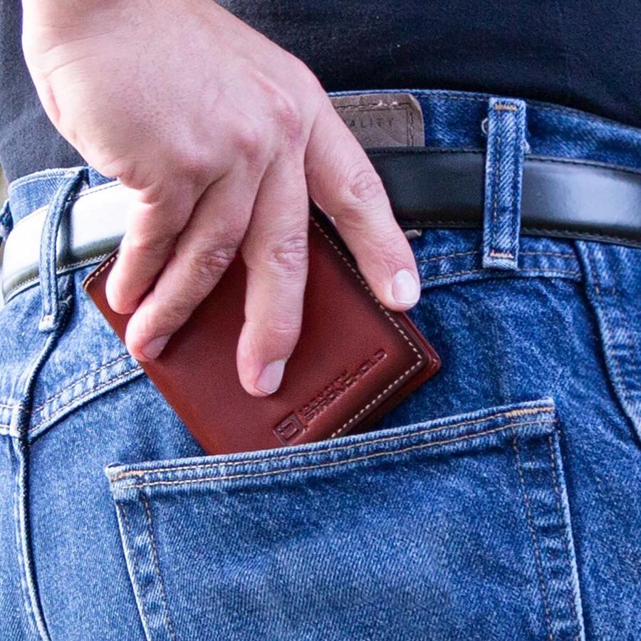 Brown leather minimalist wallet held in hand with card slot edge visible