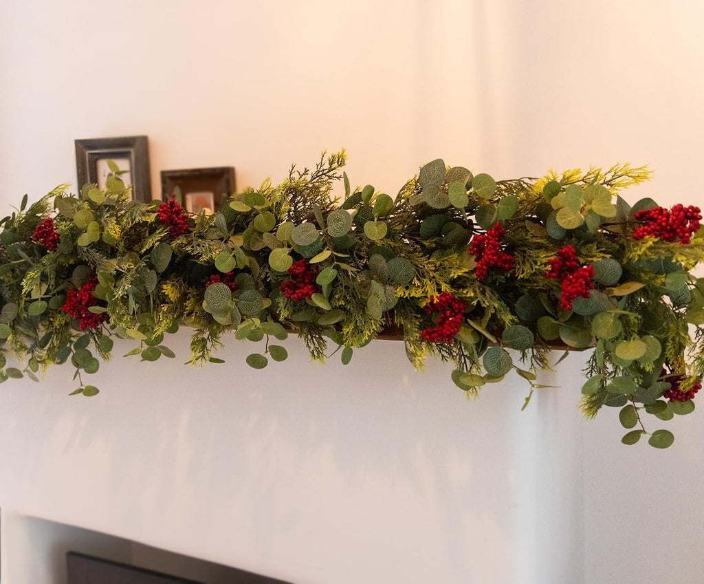 Artificial eucalyptus-style garland with pine accents and red berry clusters on wall display