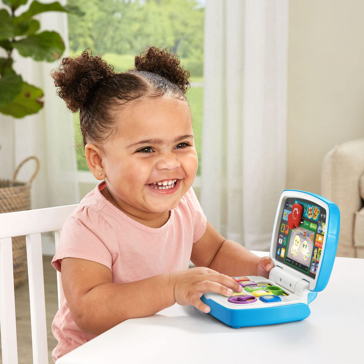 Child smiling and playing with a blue interactive toddler laptop tech toy