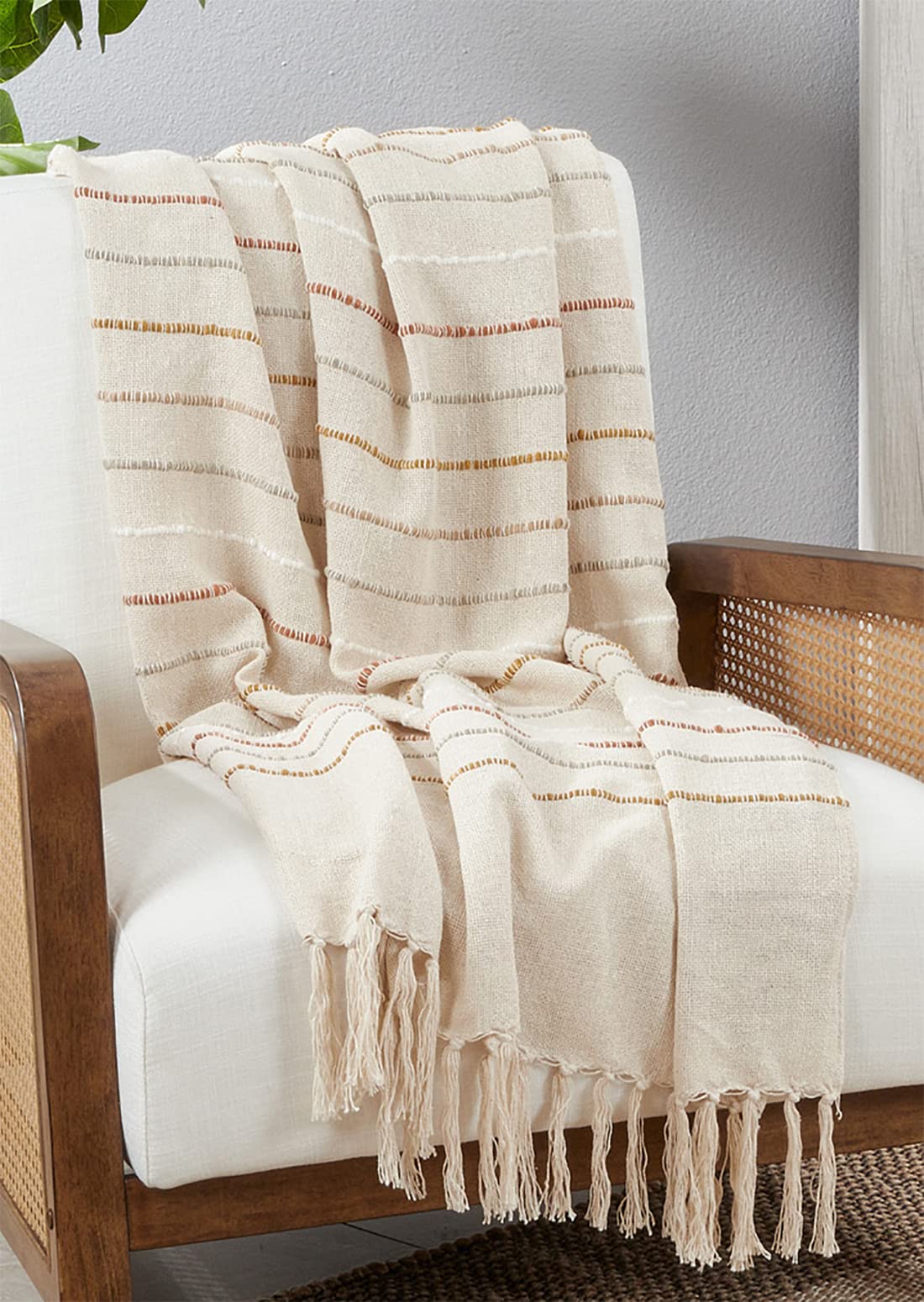 Ivory woven stripe throw blanket with tassel fringe, draped over wooden chair