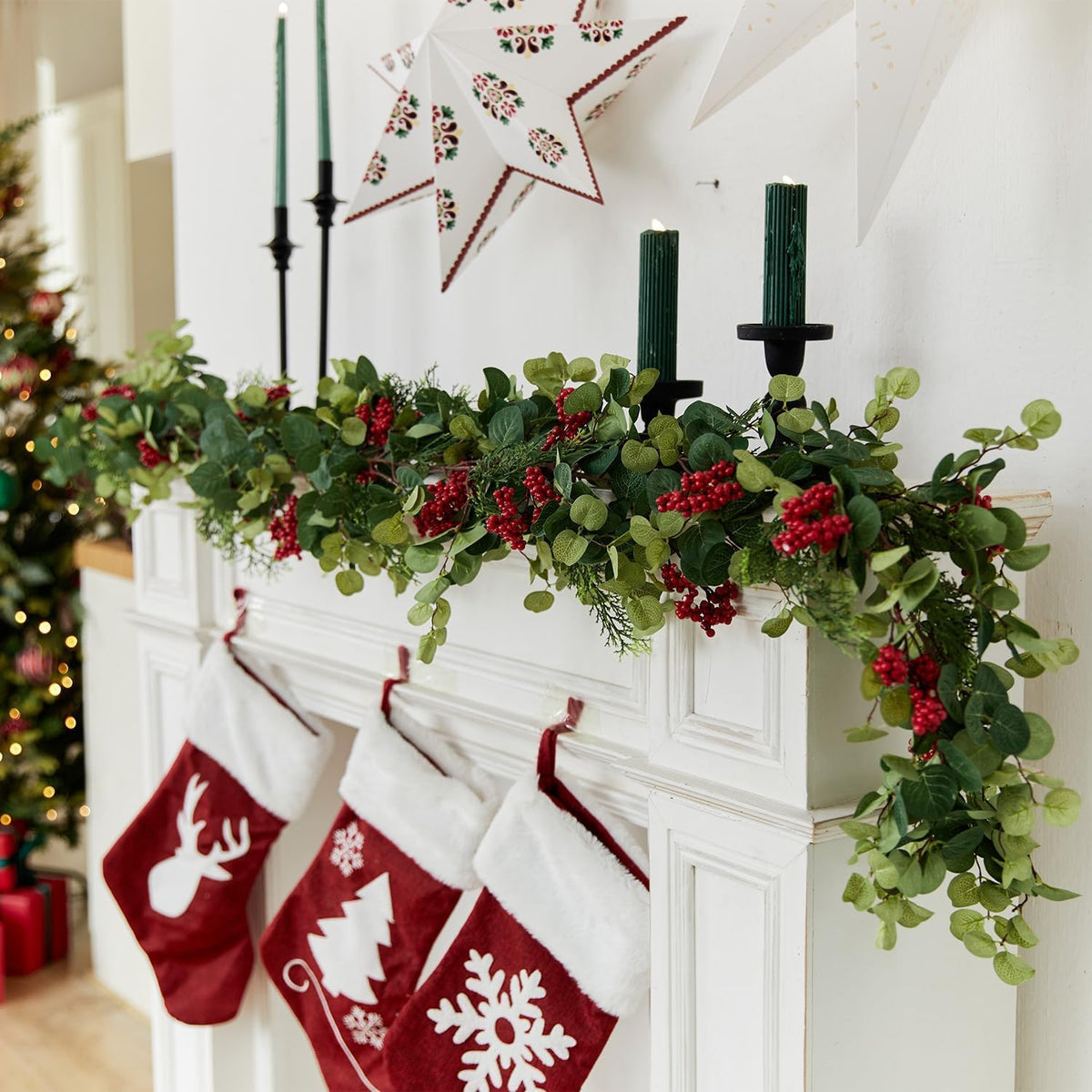 Artificial green pine garland with eucalyptus-style leaves and red berry clusters across mantle
