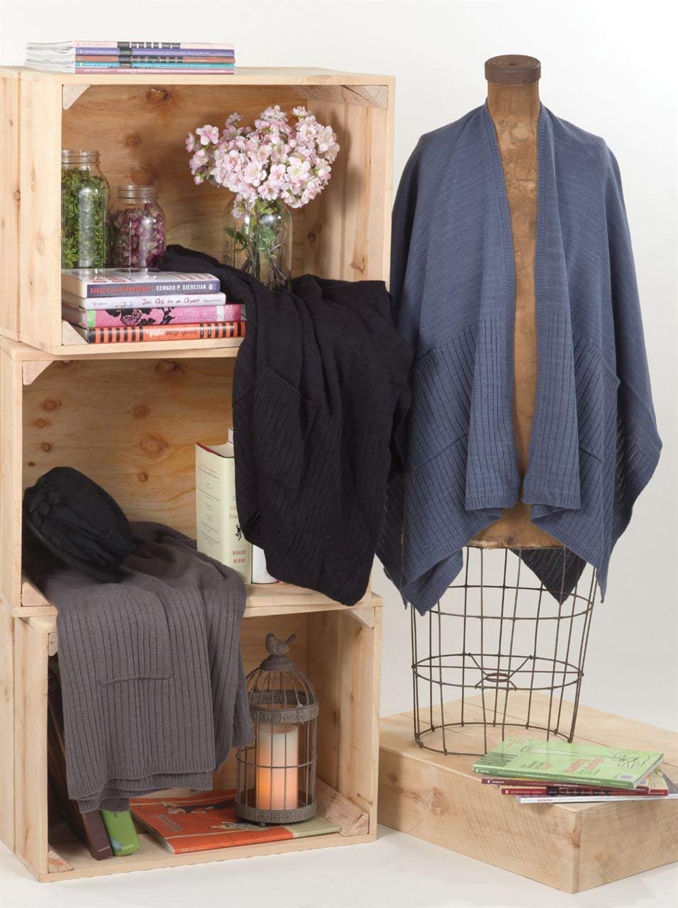 Knitted poncho capes with pockets in black and blue/gray on mannequins.