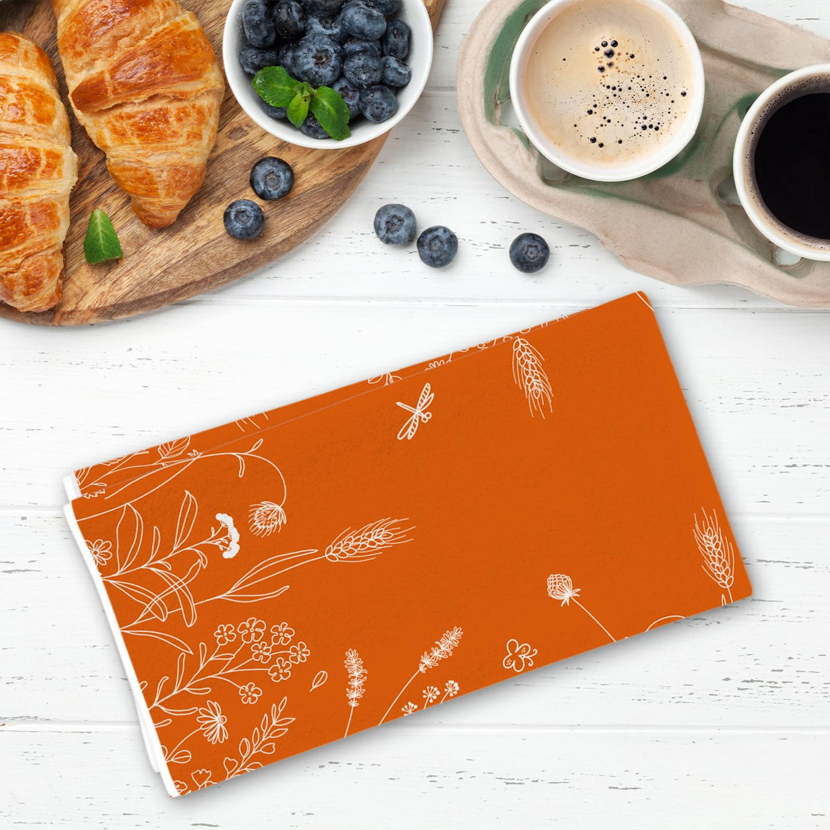 Orange kitchen towel with white floral line pattern, folded and laid flat