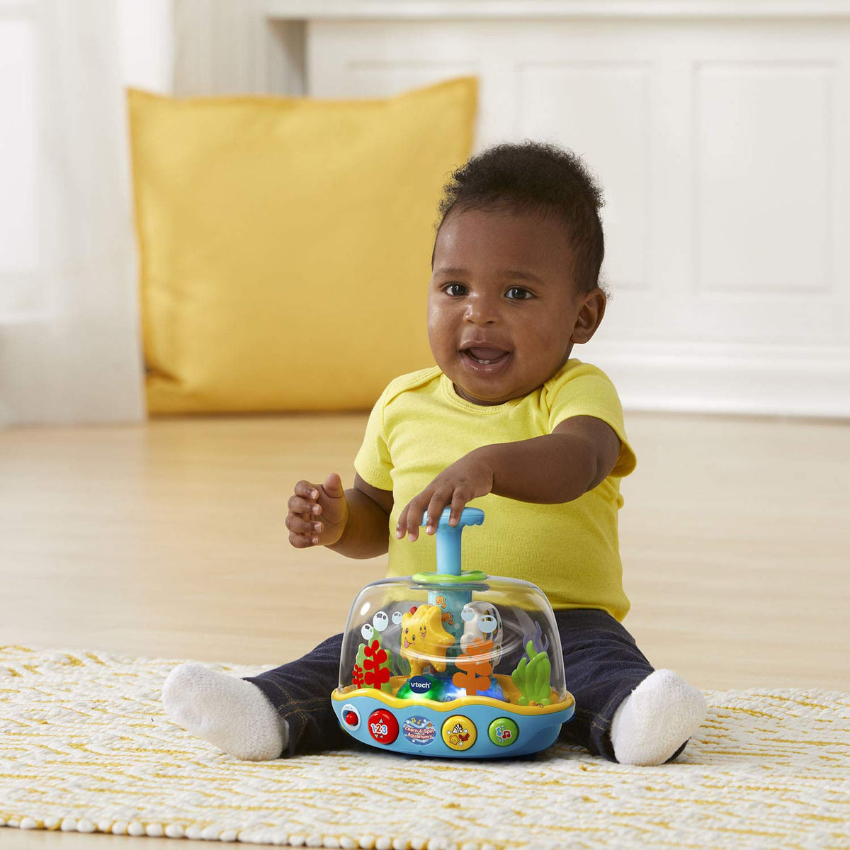 Baby seated with spinning ocean adventure aquarium toy on floor
