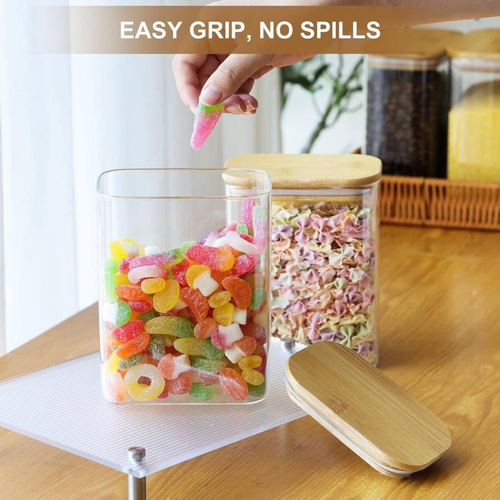 Square clear glass storage jar with bamboo lid, open top with colorful candy inside.