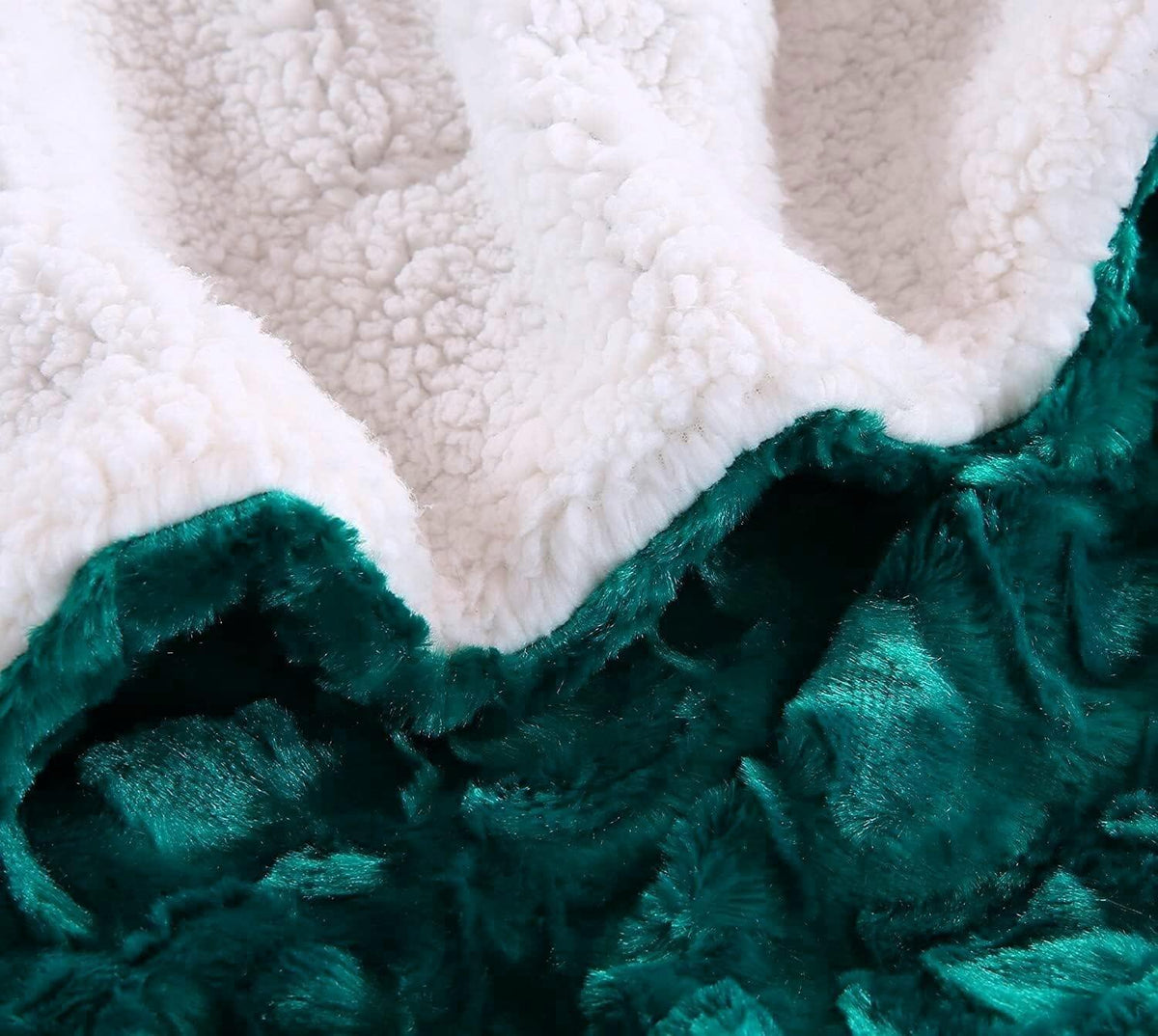 Close-up of white sherpa section with dark teal faux fur underside of a throw blanket