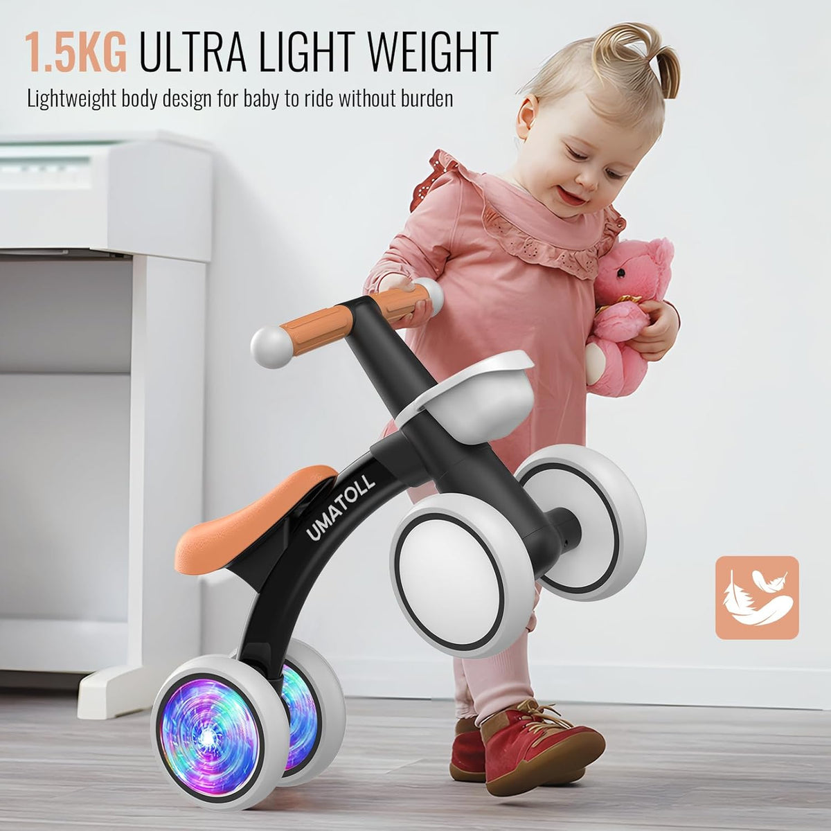 Toddler riding a black and orange balance bike with white seat and glowing front wheel