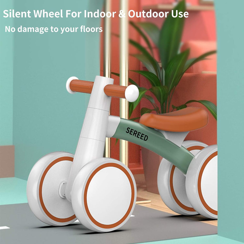 Green-frame toddler balance bike with orange seat and white wheels for indoor and outdoor use