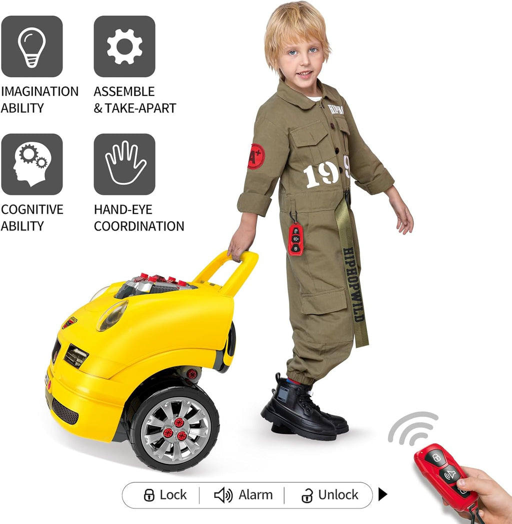 Toddler playing with yellow toy mechanic truck, wearing jumpsuit, holding remote control