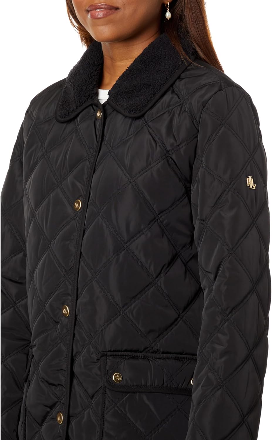 Black quilted jacket close-up with berber-trim collar, gold buttons, logo patch