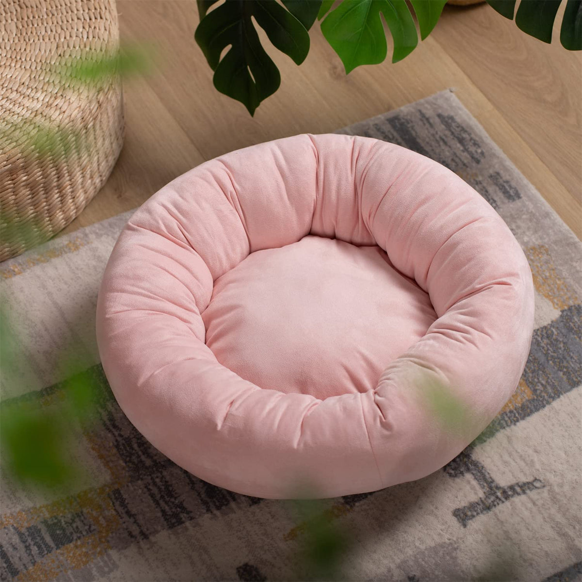 Pink round dog bed cushion with deep rim, set on a patterned rug.