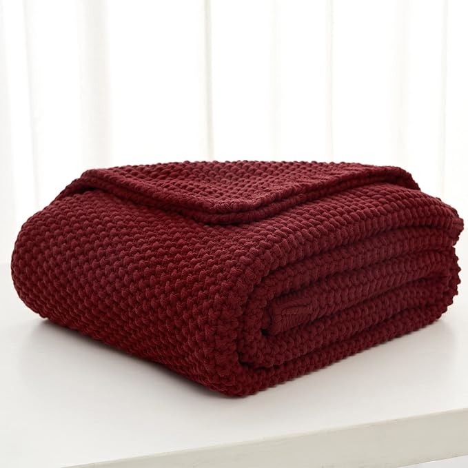 Burgundy chunky cable-knit throw blanket neatly folded on a light surface