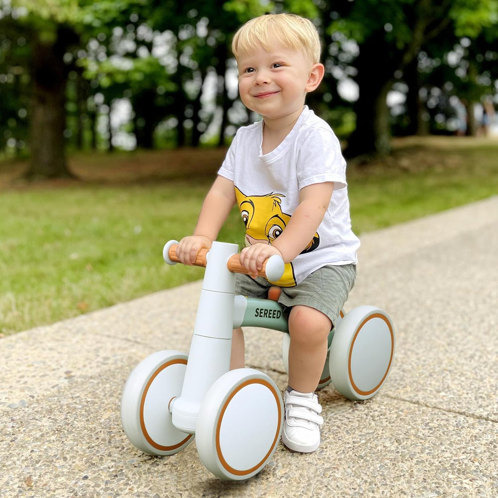 Toddler riding balance bike: green frame, orange seat, white wheels with orange trim
