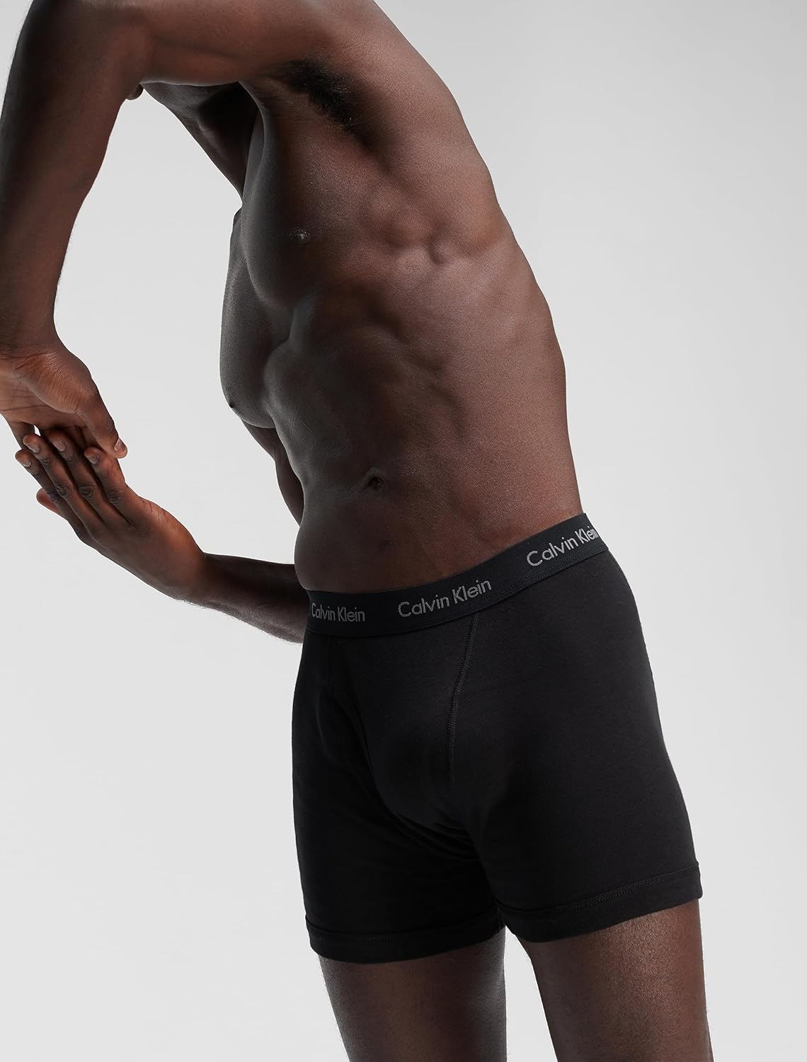 Men's black boxer briefs with Calvin Klein logo waistband, side view on model