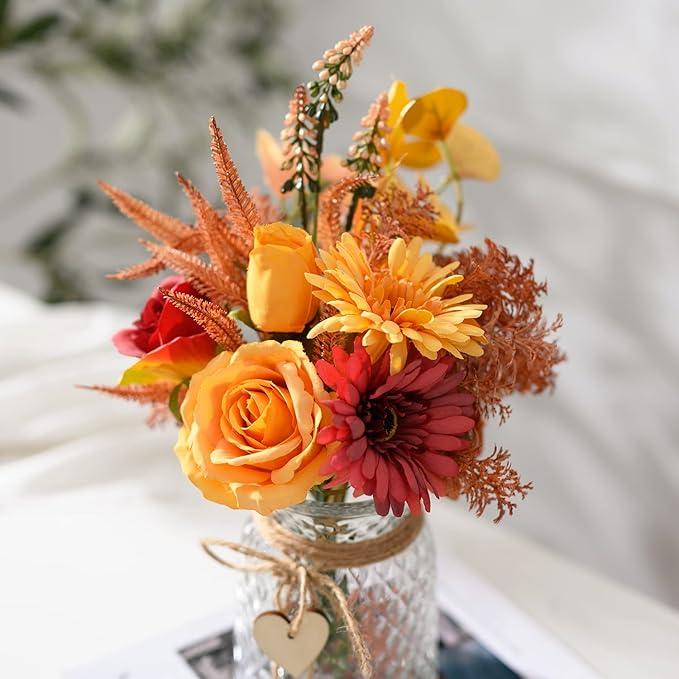 Close-up faux flower bouquet in textured glass vase with orange rose and red blooms