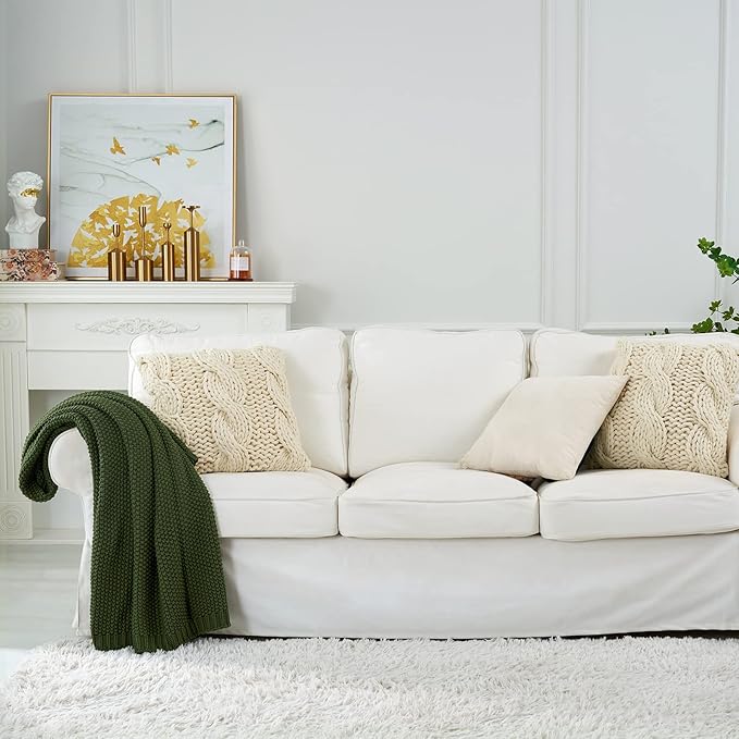 Olive green chunky knit throw blanket draped over a white couch back