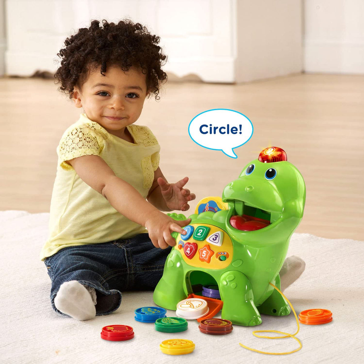 Green counting dinosaur toy with mouth opening and colorful number buttons, shown with baby