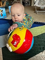 Baby holding red-and-blue rolling ball with animal graphic