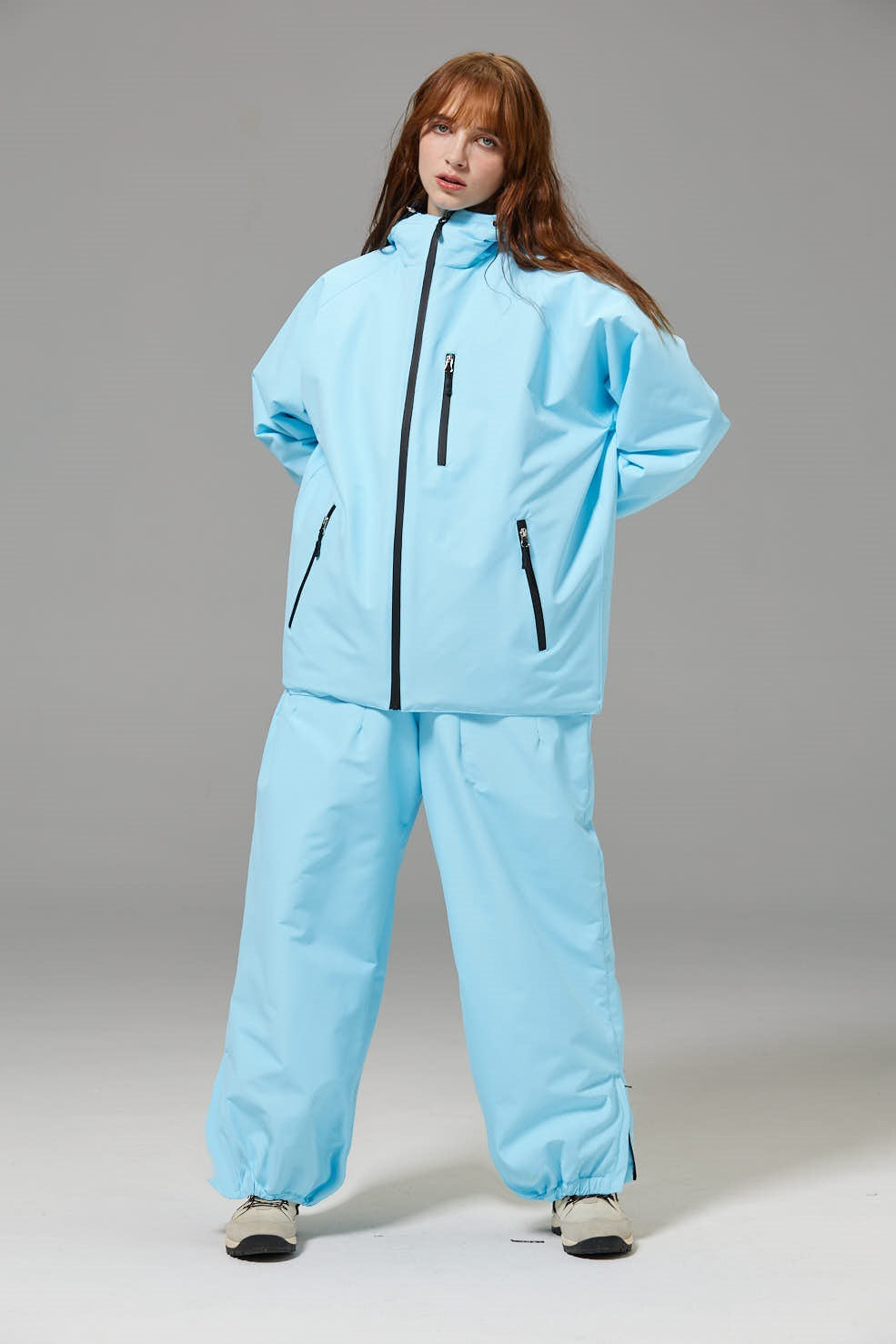 Light blue unisex ski suit set with hooded jacket, black zipper, and matching loose pants