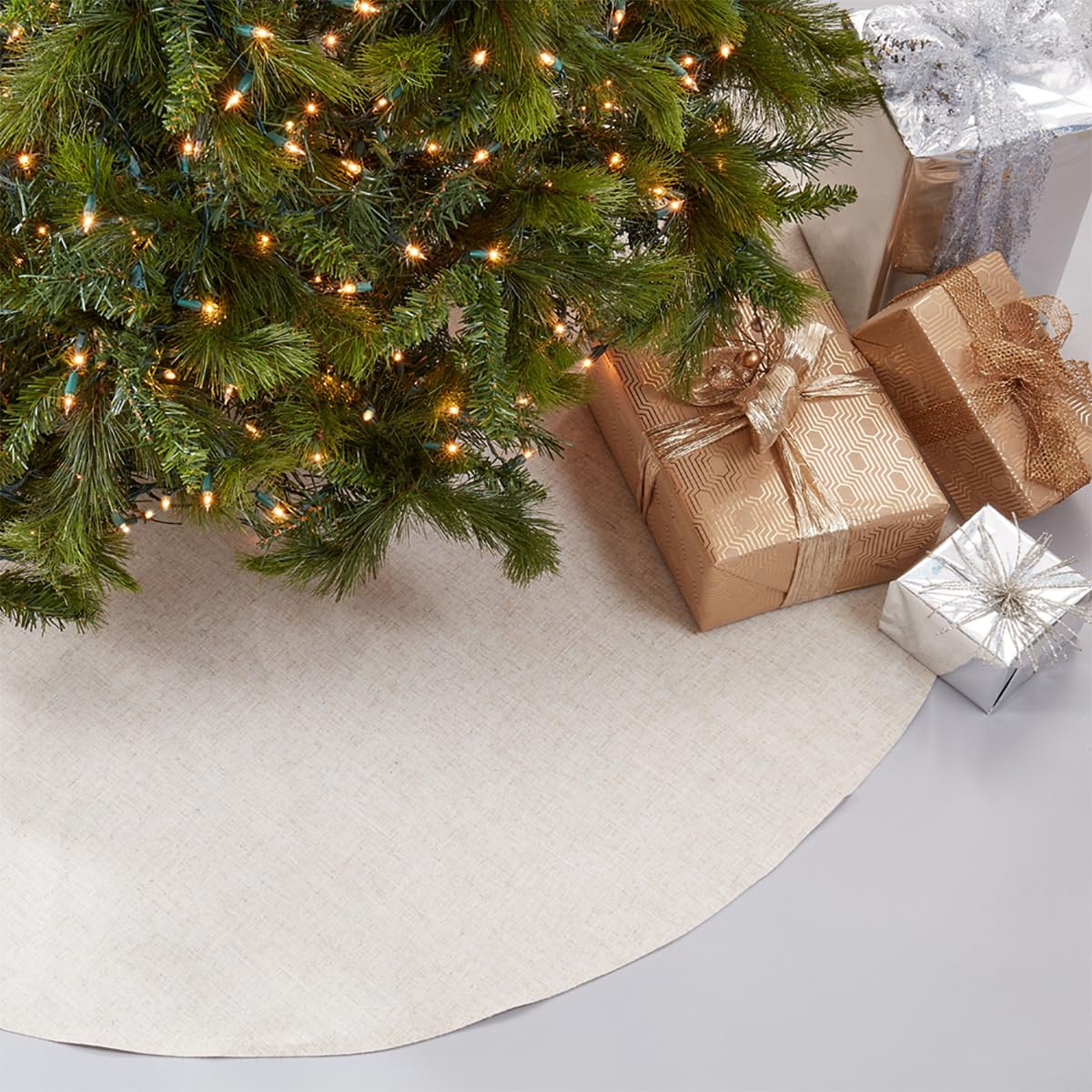 Natural round Christmas tree skirt with curved edge under a lit tree