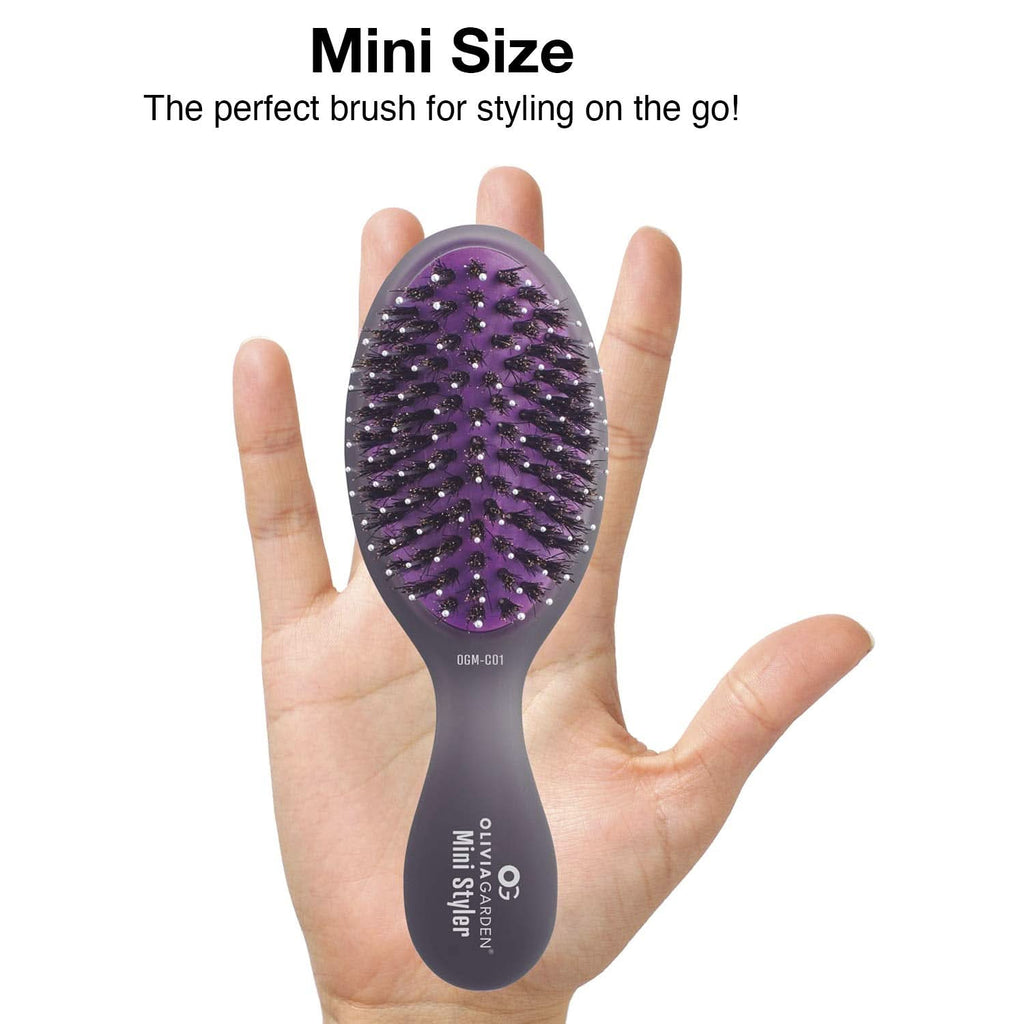 Mini purple hair brush with black bristles, held in a hand for on-the-go styling.