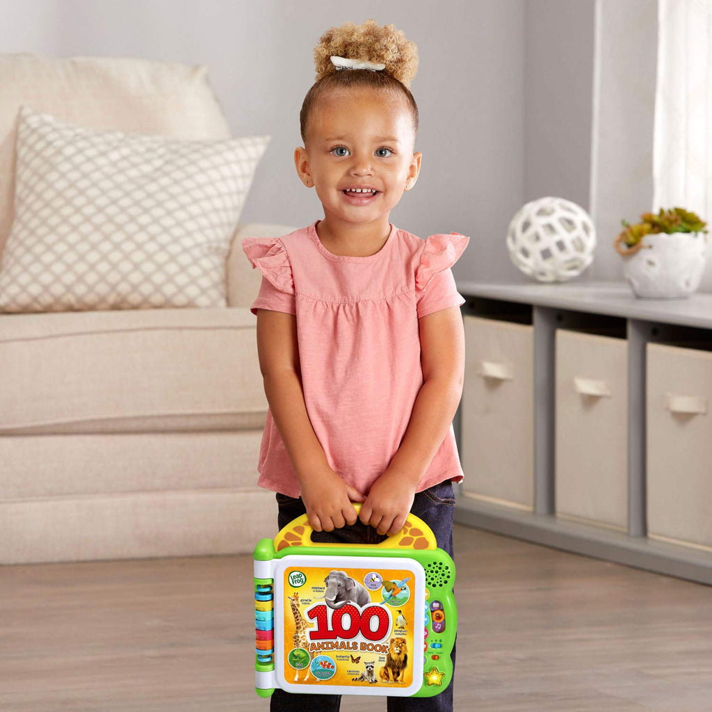 Baby holds green interactive 100 animals book toy with animal cover artwork