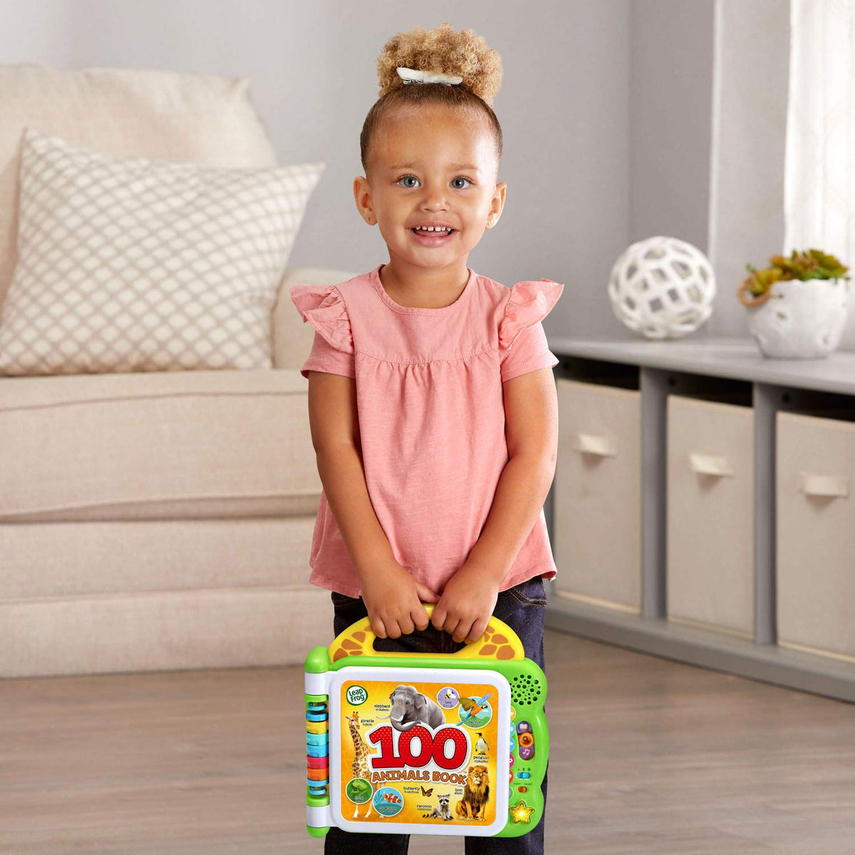 Baby holds green interactive 100 animals book toy with animal cover artwork
