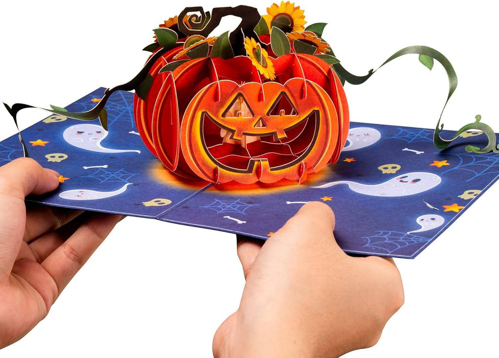 Open Halloween pop-up pumpkin card held by hands with jack-o'-lantern and sunflower accents