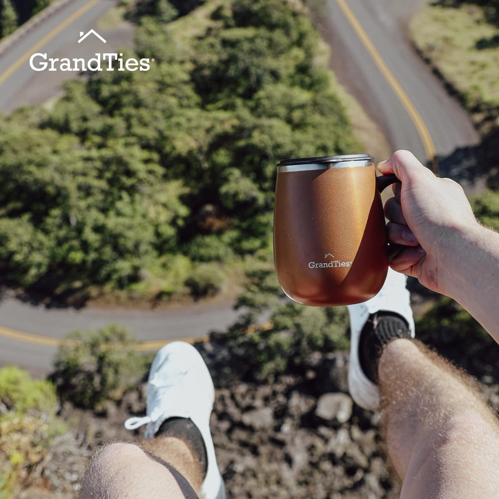 Insulated coffee mug with handle in cognac metallic, hand holding near the road