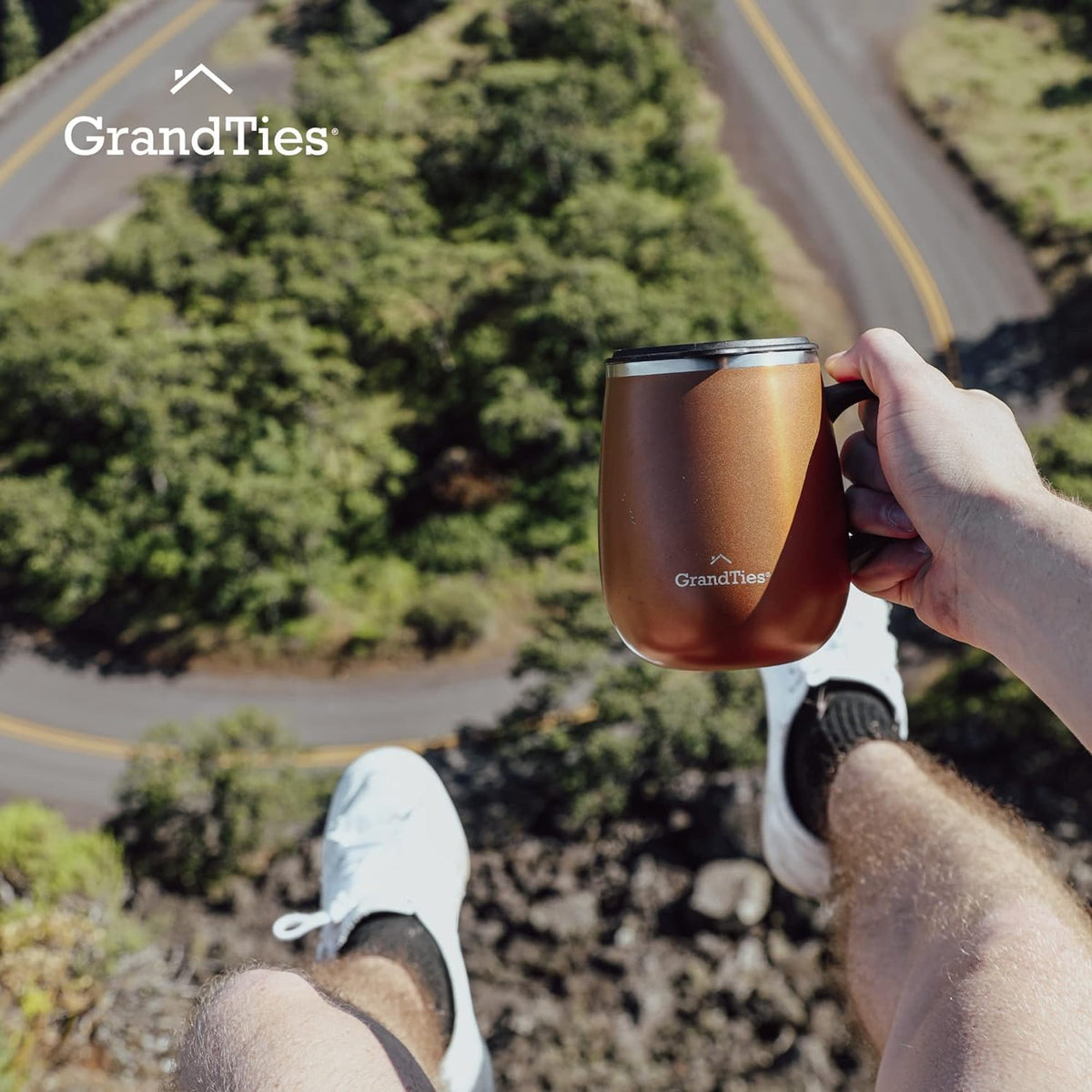 Insulated coffee mug with handle in cognac metallic, hand holding near the road