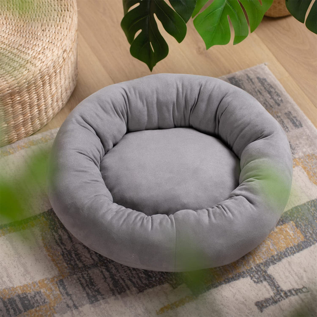 Grey round dog bed cushion with tufted rim and smooth inner sleeping area.