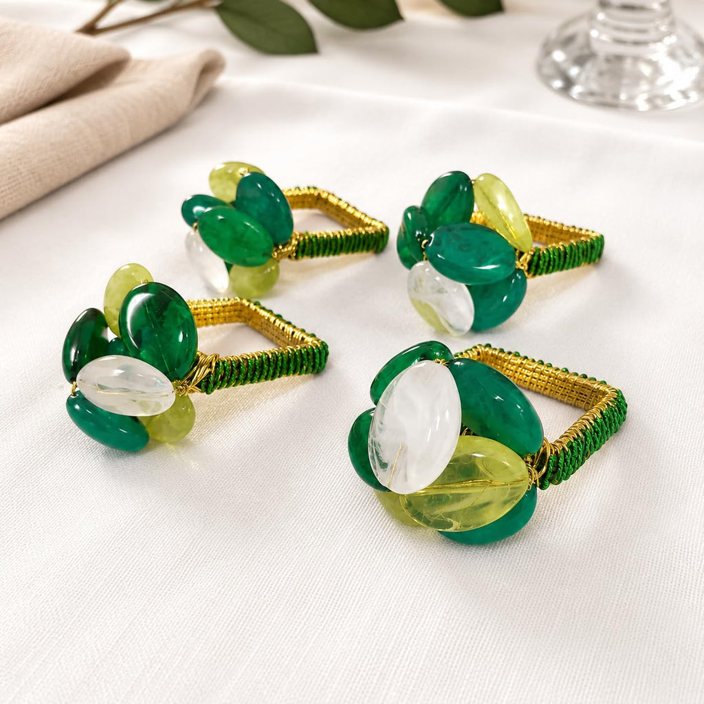 Close-up gemstone beaded napkin rings with green and white stones on gold bands
