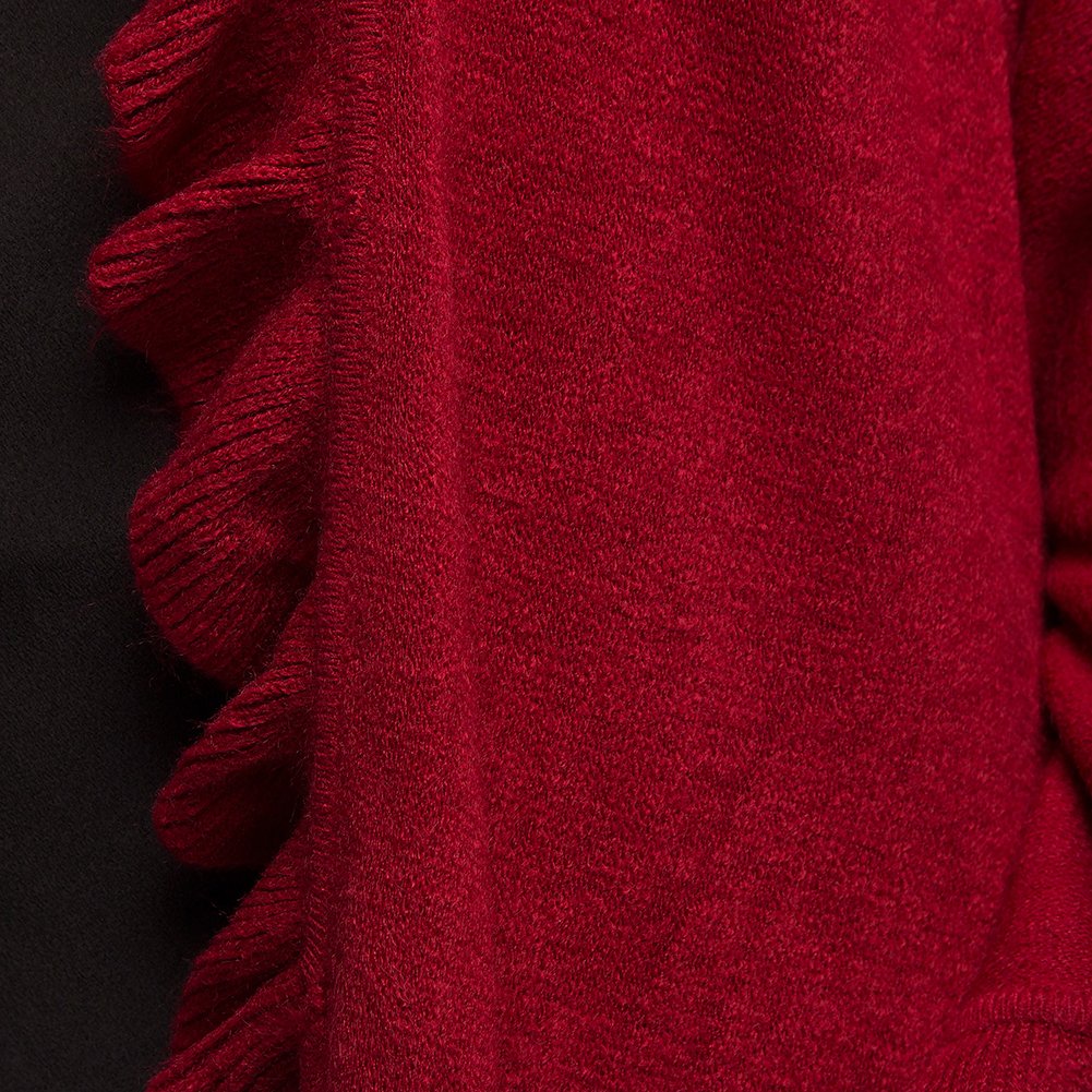 Close-up of crimson red knit poncho fabric with ruffled trim detail