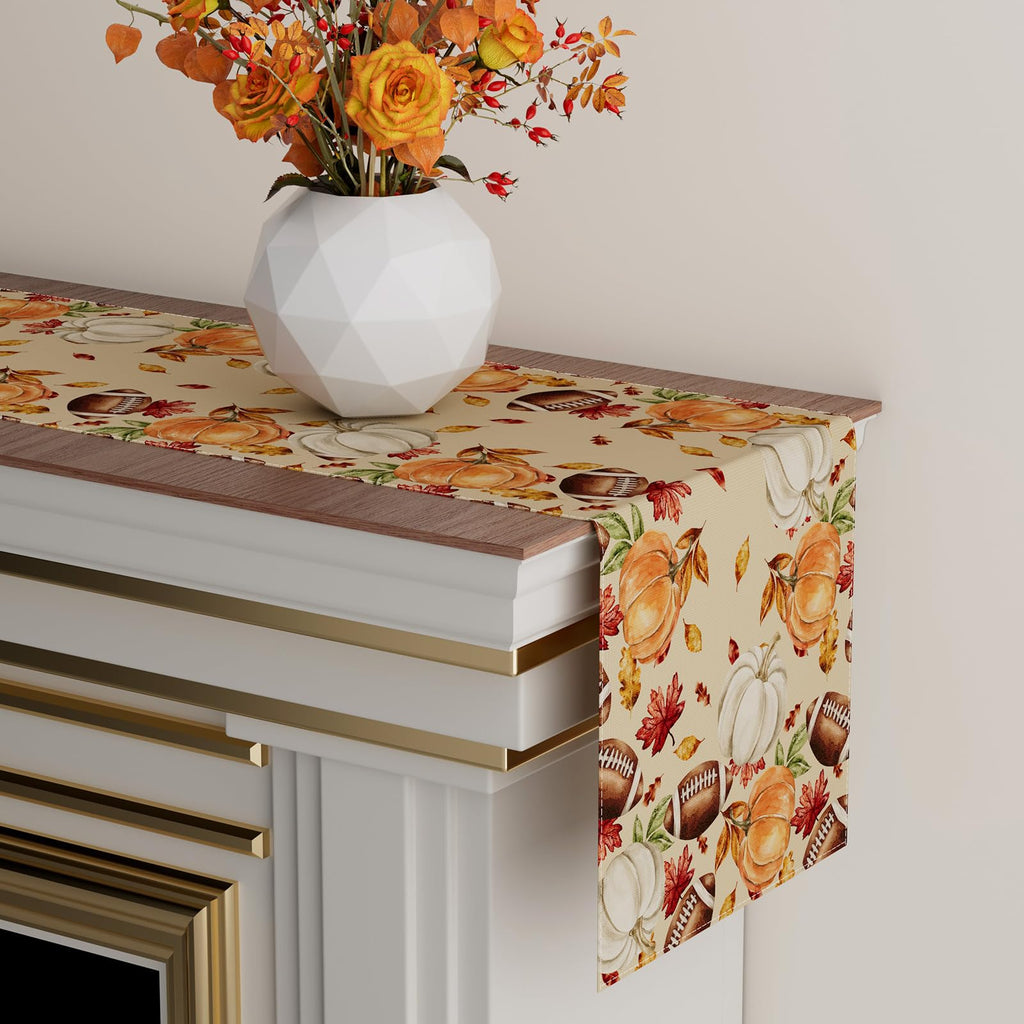 Draped corner of fall table runner with pumpkins, leaves, and football motifs