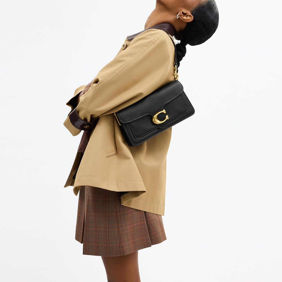 Black quilted leather shoulder bag with gold chain strap, worn crossbody with front clasp.