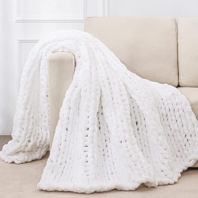 White chunky knit throw blanket with rope-knot cable texture, draped over a sofa