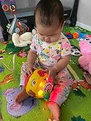 Baby holding a yellow plush ball with textured surfaces and glowing light bulbs