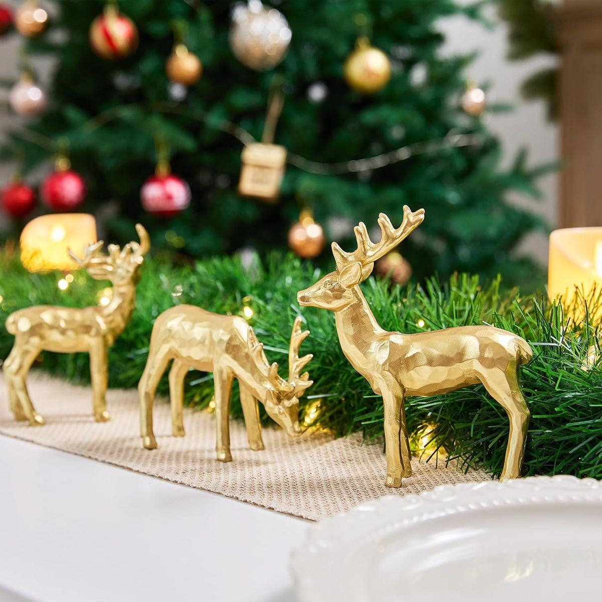 Gold resin reindeer figurines on a green garland runner, three standing deer