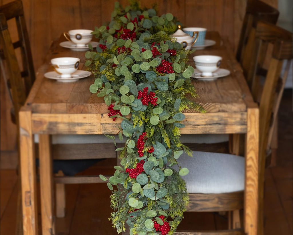 Decorative table garland centerpiece with green eucalyptus leaves and red berry sprigs