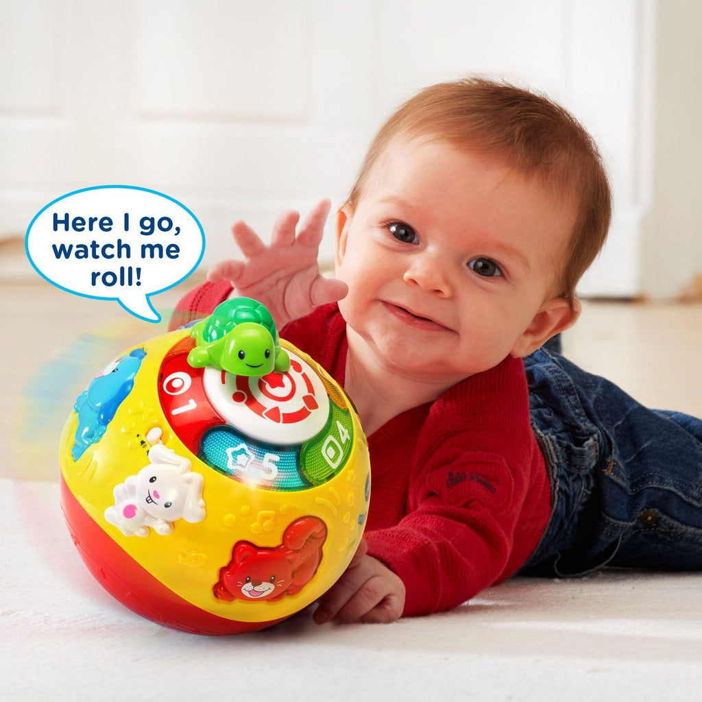 Baby holding yellow rolling ball with green turtle top and numbered light panel