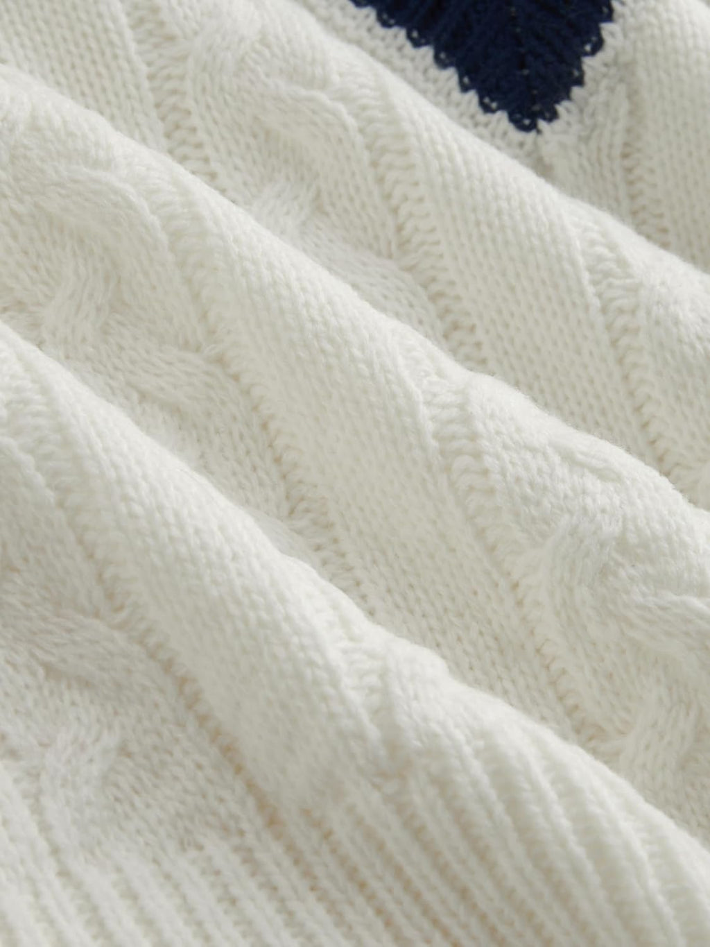 Cream cable-knit sweater fabric with raised cable texture and ribbed trim
