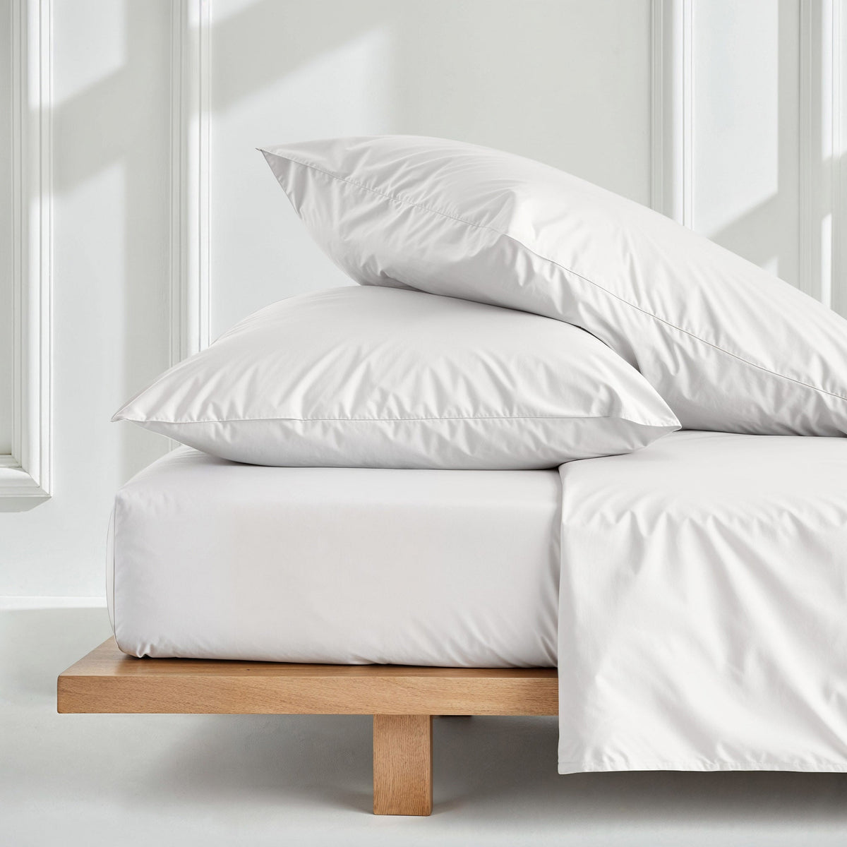 White sateen bedding bundle with pillows and neatly folded duvet on bed