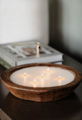 Wooden bowl candle with lit wicks, creamy white wax in a dark wood bowl