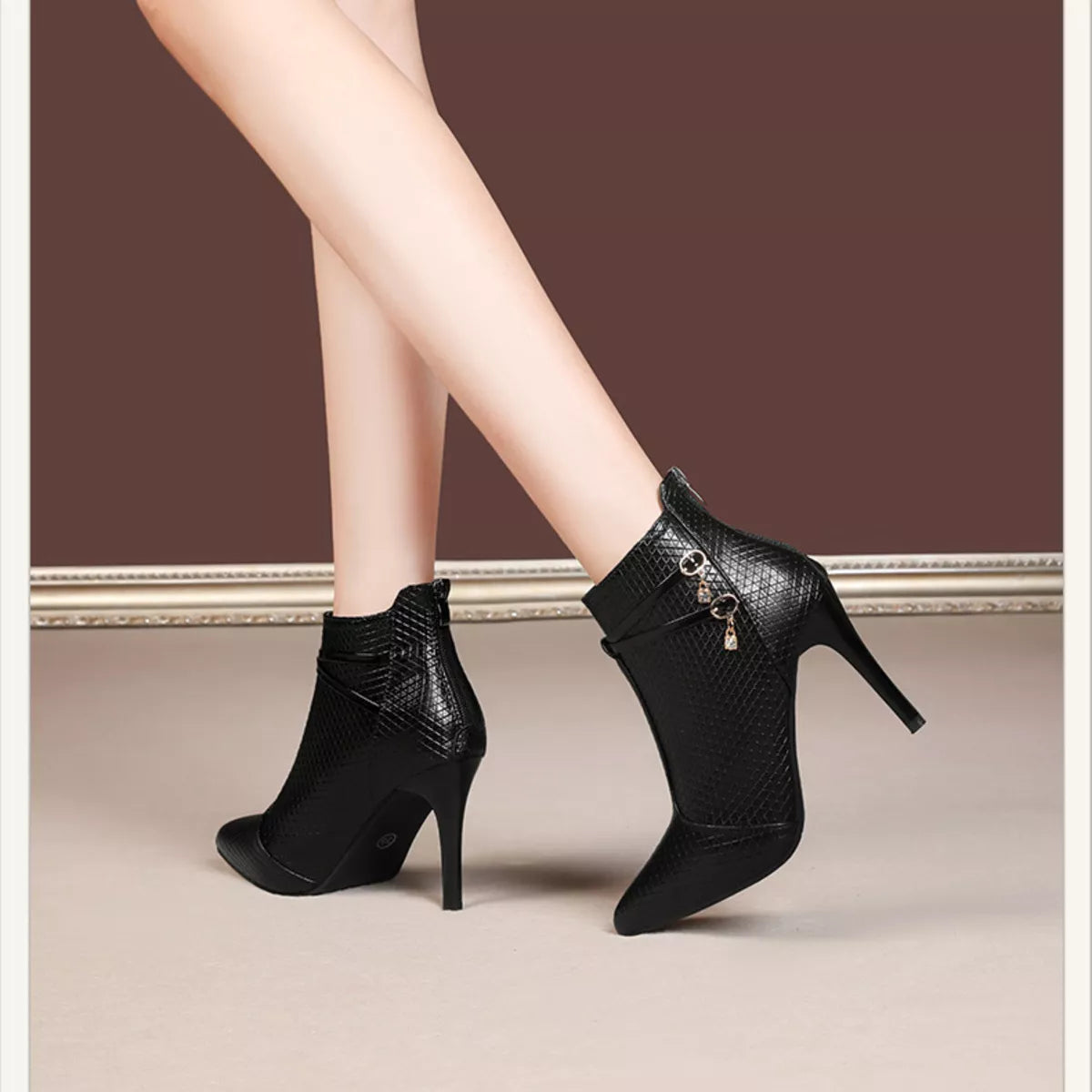 Black pointed-toe stiletto ankle boots with textured upper and dangling chain trim
