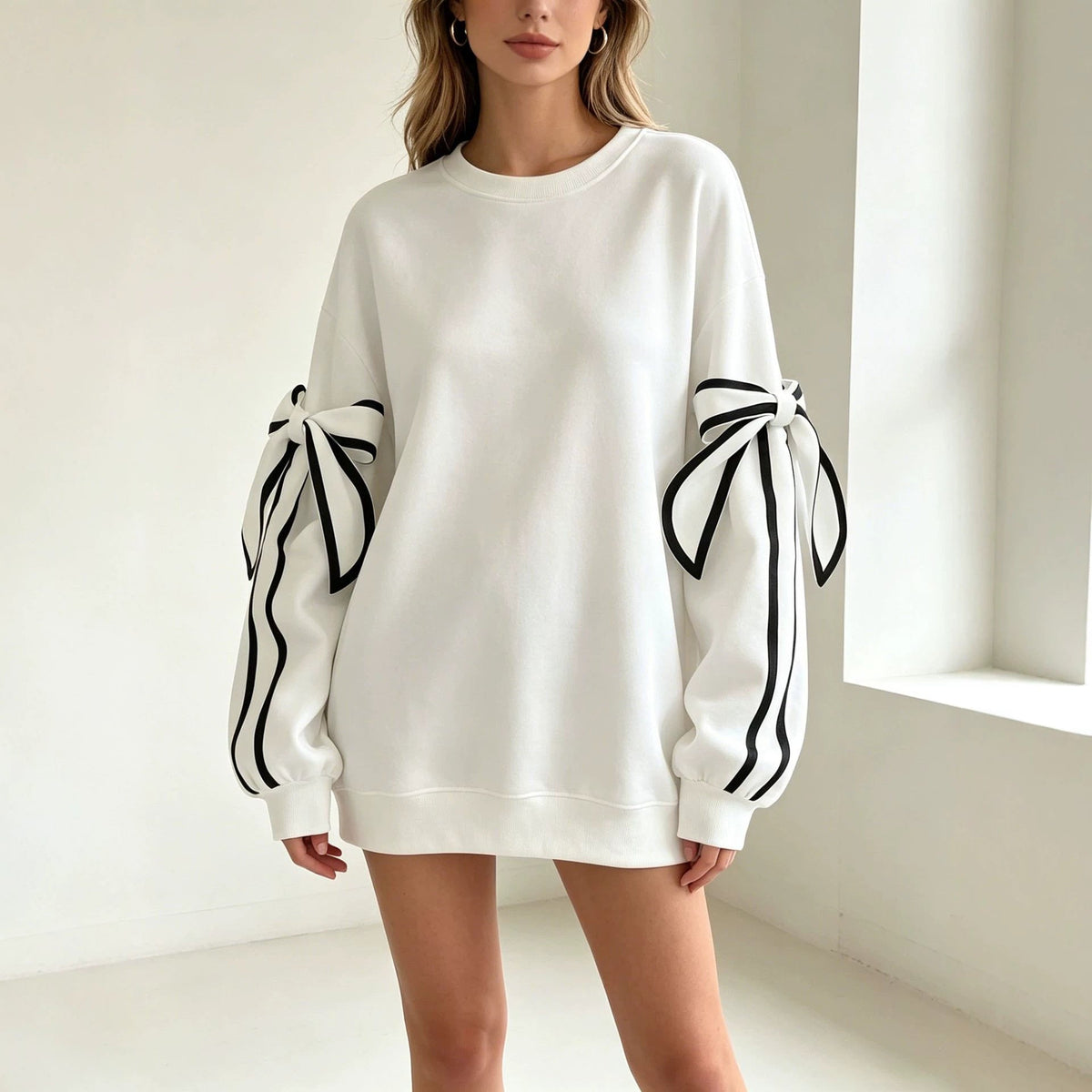 White crewneck long-sleeve sweater with black striped bow cuffs on both sleeves.