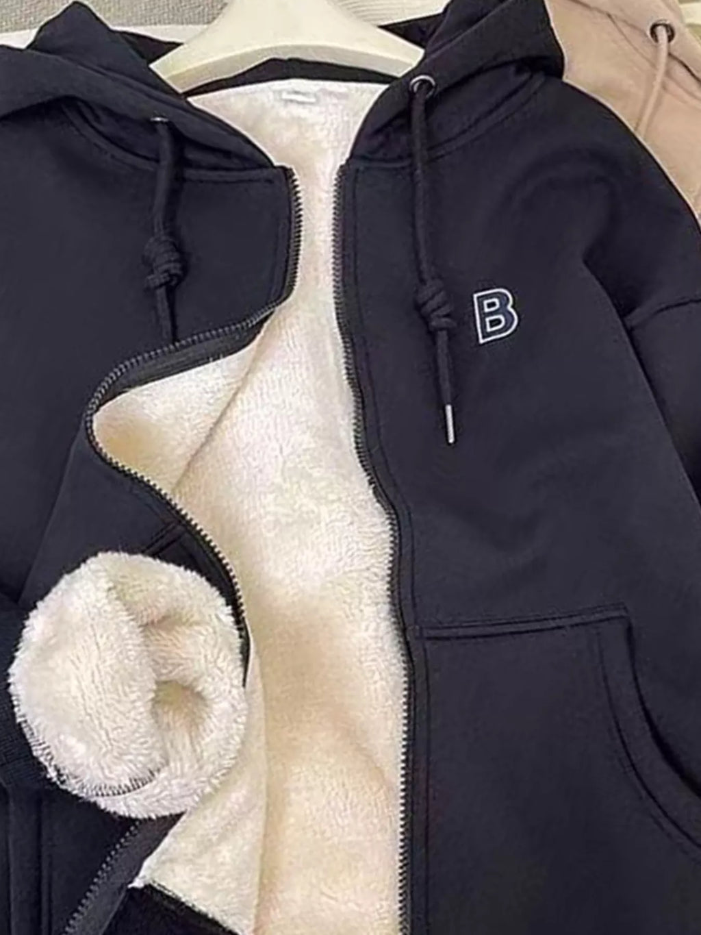 Dark navy fleece-lined zip-up hoodie close-up: front zipper, hood drawstrings, sherpa lining.