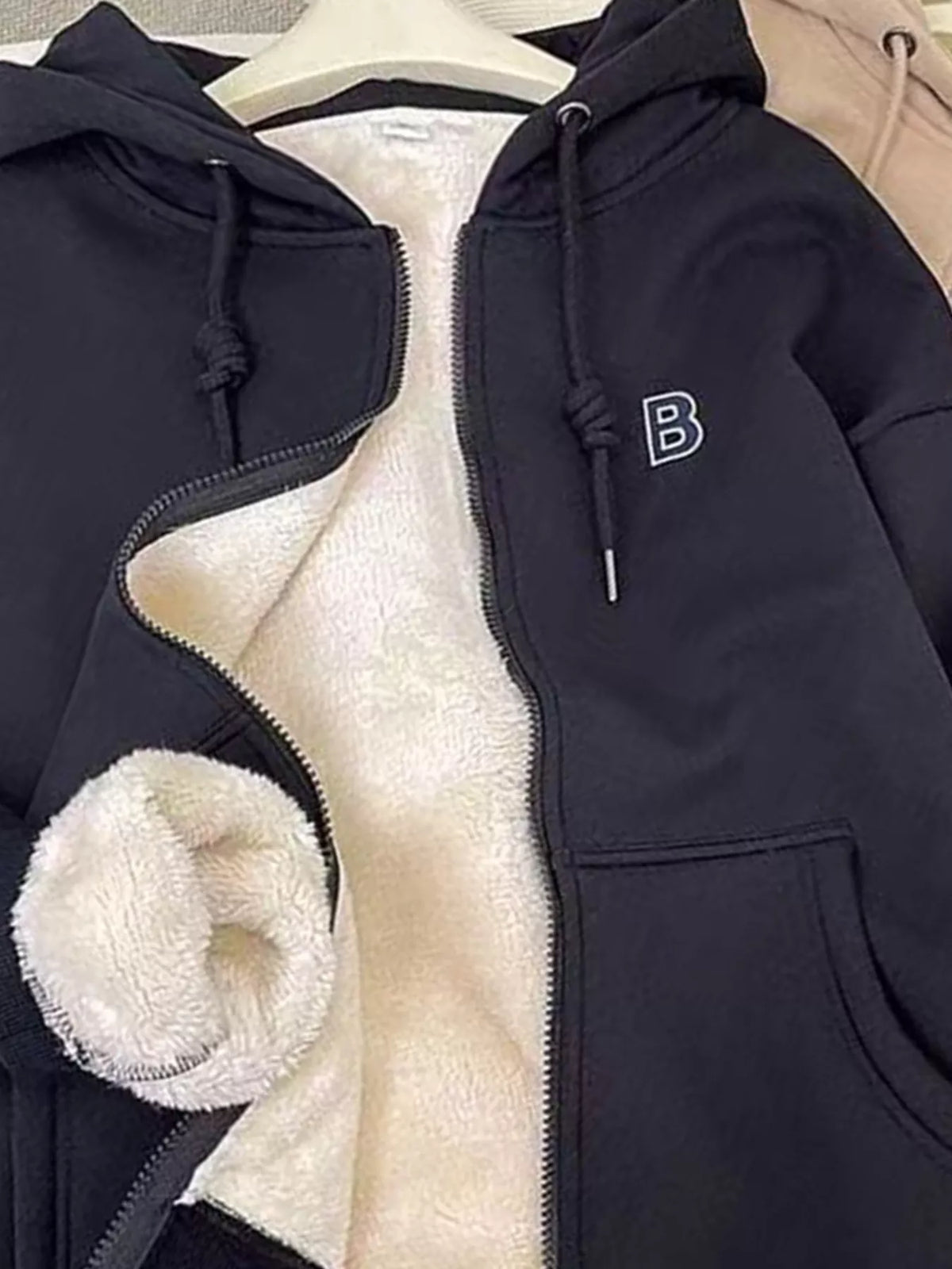 Dark navy fleece-lined zip-up hoodie close-up: front zipper, hood drawstrings, sherpa lining.